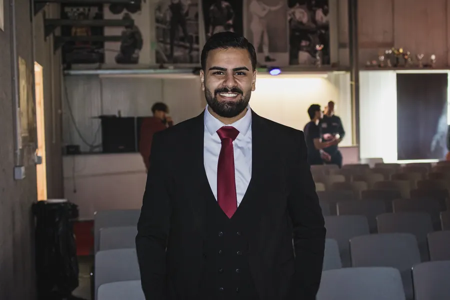 Umut Yagmur lächelt im Saal, hinter ihm Stuhlreihen